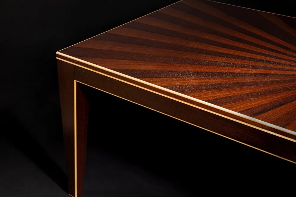 The corner of a hand crafted table with a sunburst finish