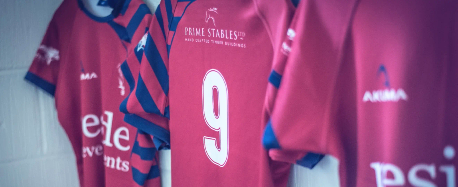 Close-up of red and navy striped Cranleigh RFC rugby shirts hanging up, showing sponsor logos and a number 9