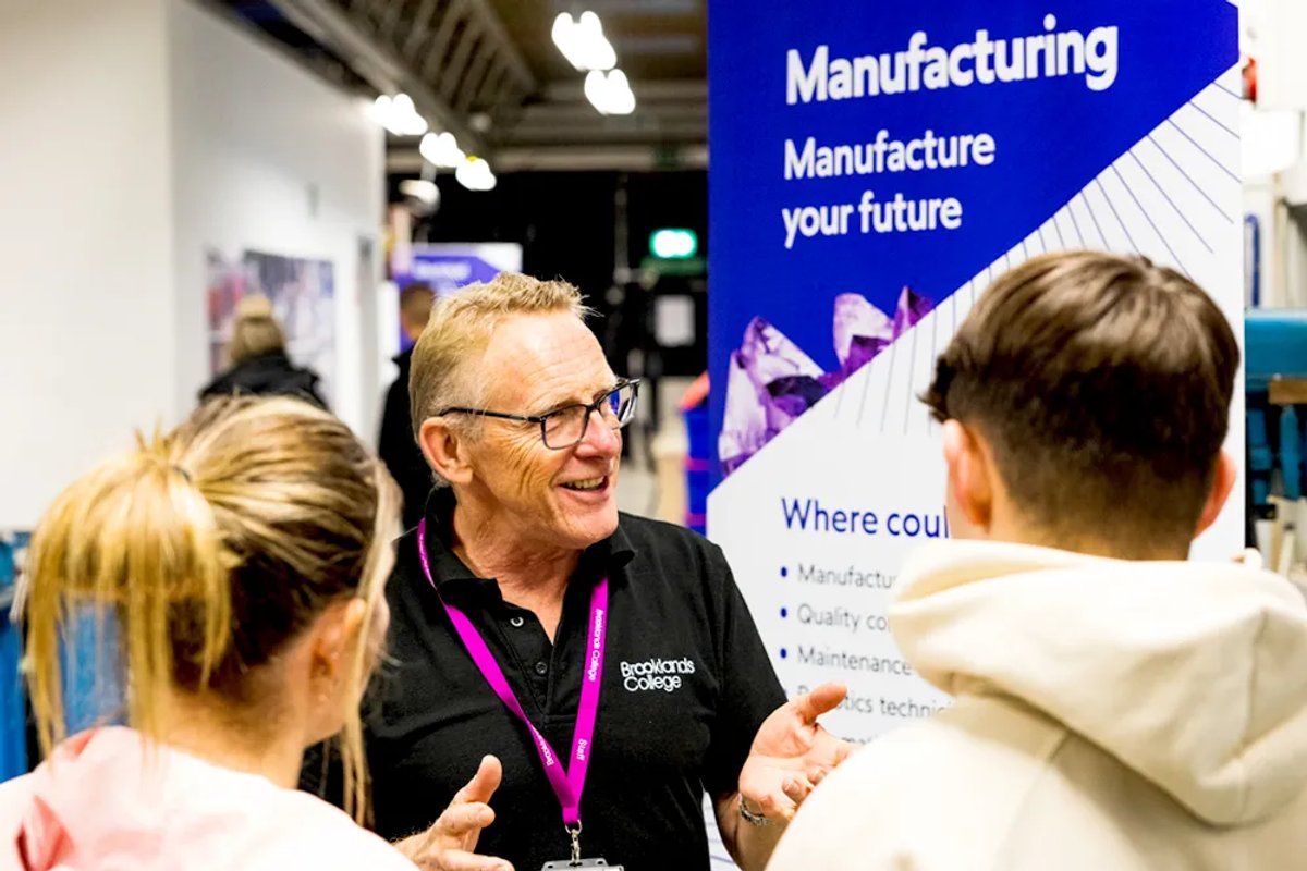 A man from Brooklands explaining something to two prospective students
