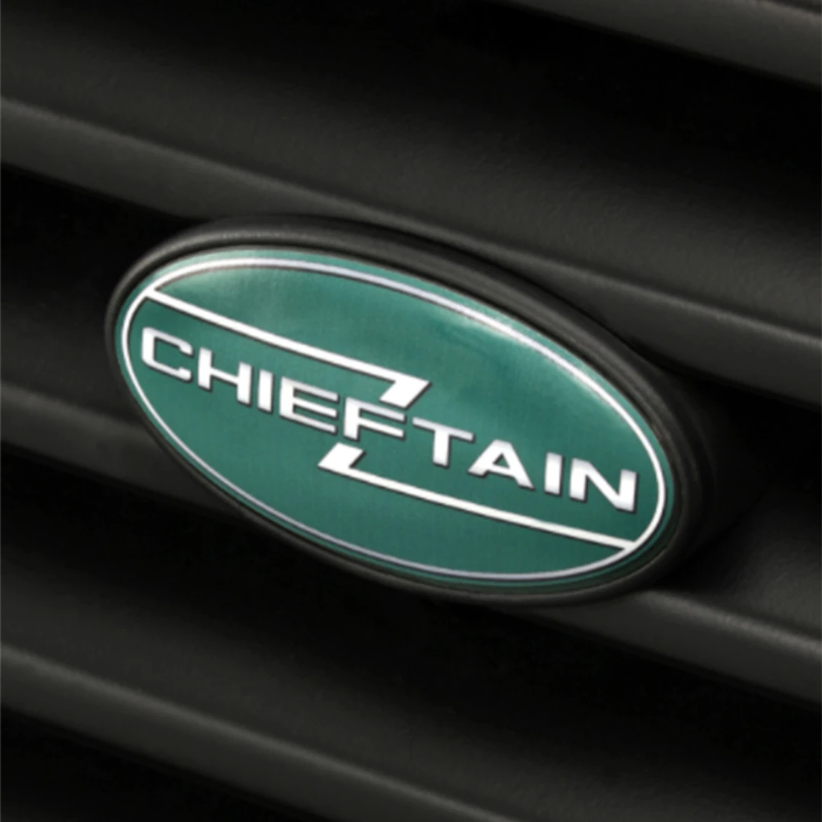 A close-up of the green and white oval Chieftain badge on the front grille of a Range Rover