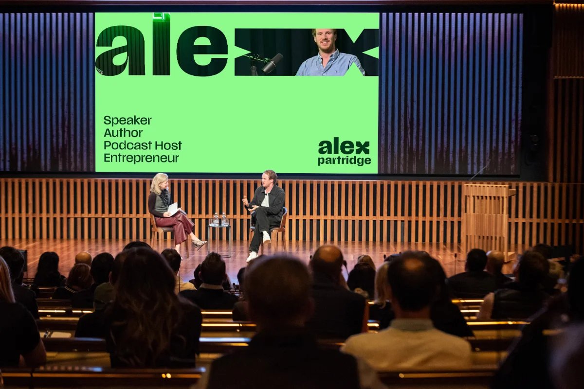 Alex Partridge on stage with his branding in the background