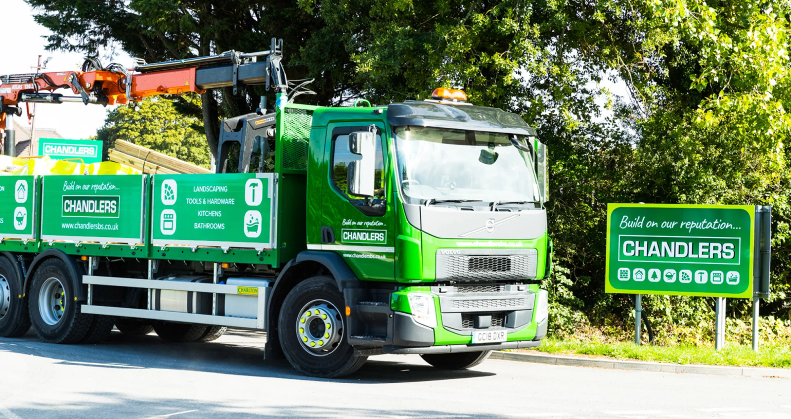 A man in a hi-vis vest and hard hat pointing to category icons on the back of a branded Chandlers grab lorry