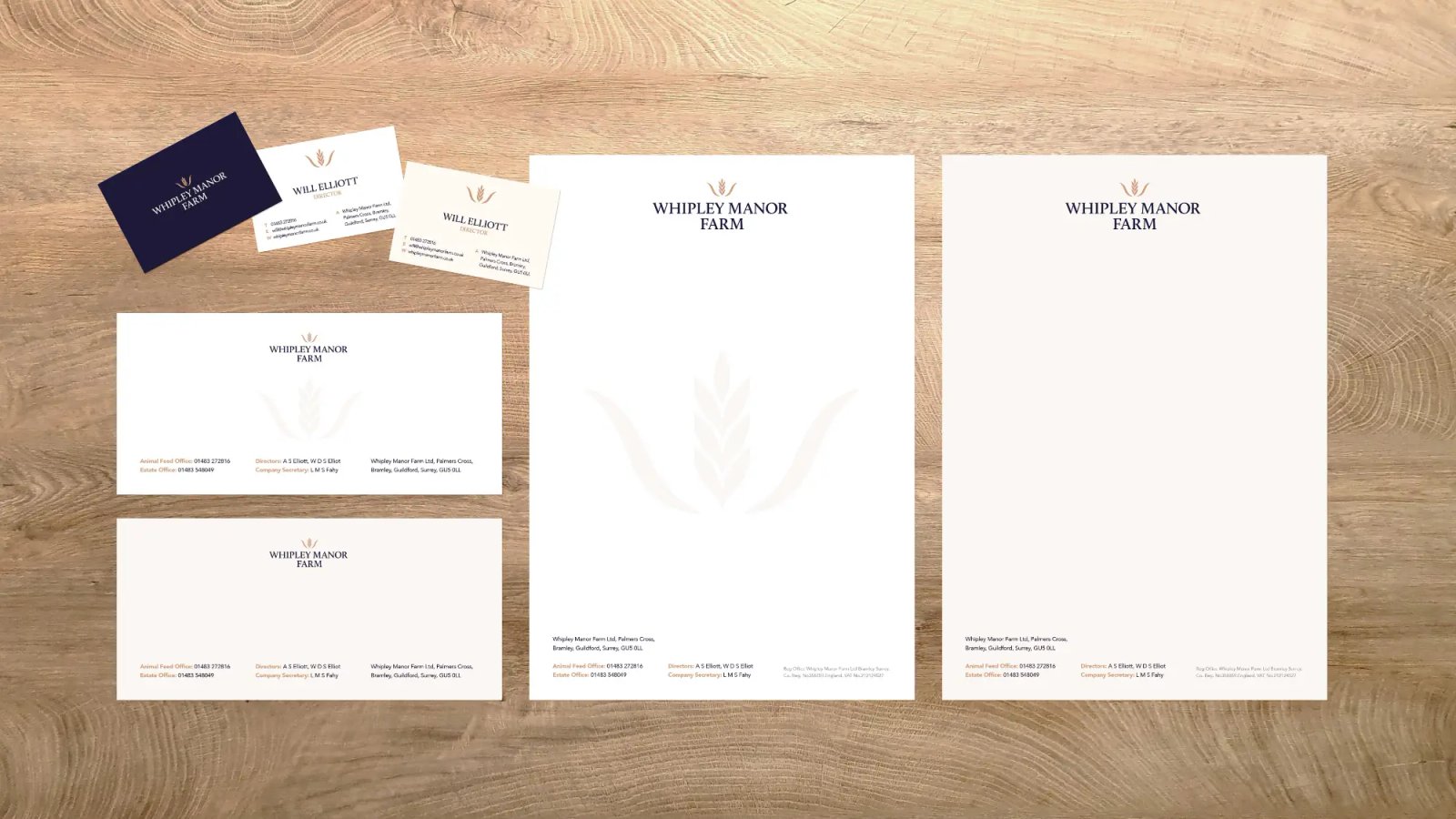 Overhead view of Whipley Manor Farm branded business cards, envelopes and letterheads arranged on a light wood surface.