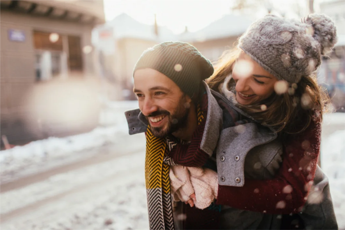 A happy man giving a piggy back to a woman