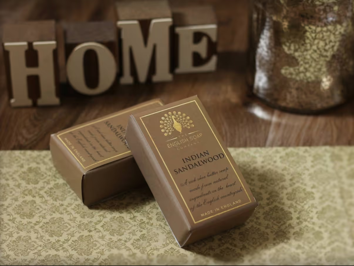 A block of sandalwood soap in packaging, with the word home written in blocks in the background