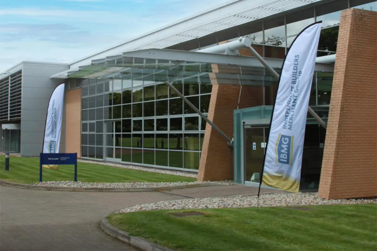 Exterior of the IBMG headquarters building with branded flag banners either side of the entrance