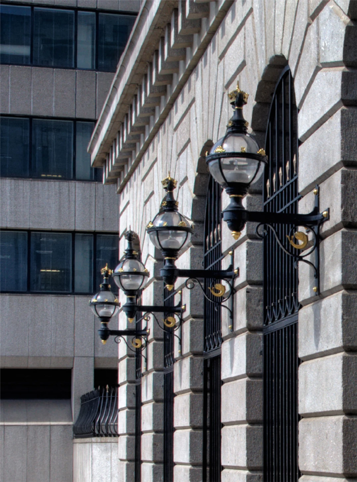 A row of ornate black and gold lanterns mounted on the stone exterior of Fishmongers' Hall