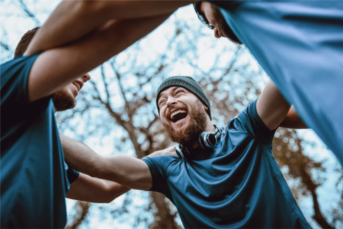 Smiling men outdoors in a circle embracing