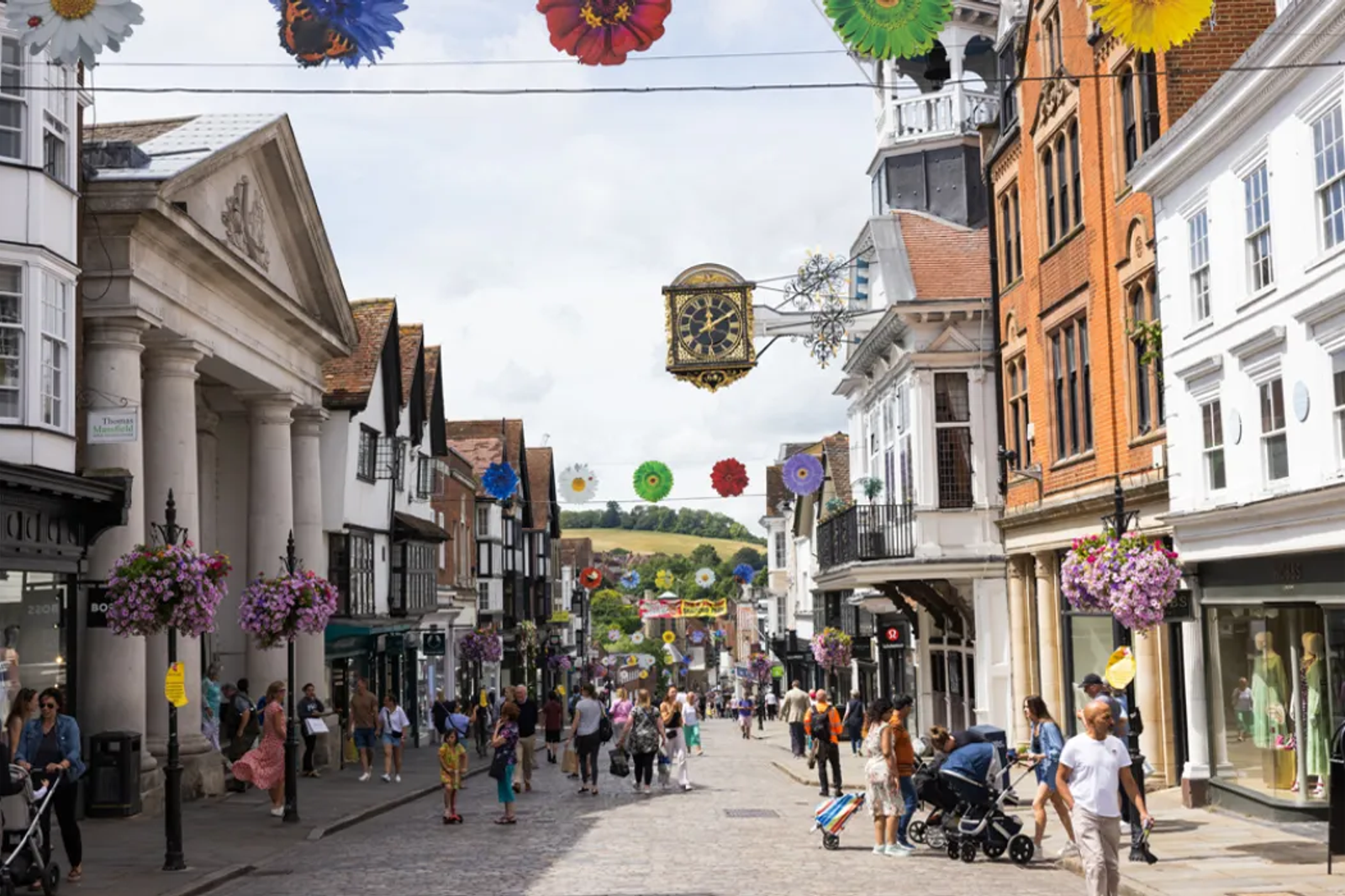 Photograph looking down a busy Guildford High Street full of people.