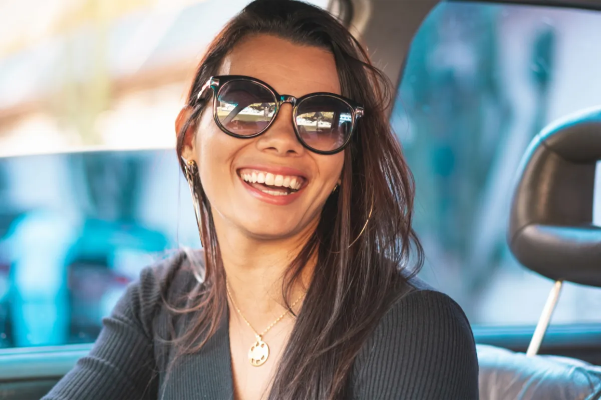 Woman in sunglasses in a car smiling