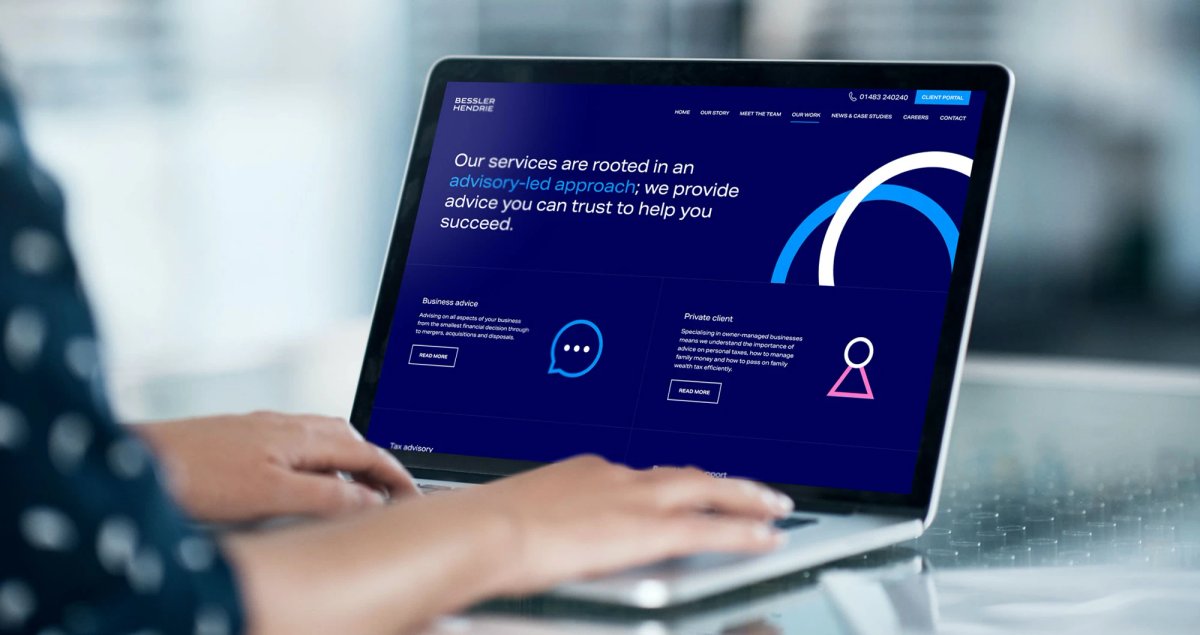 A person typing on a laptop displaying the Bessler Hendrie website, showing the 'Our services are rooted in an advisory-led approach' headline