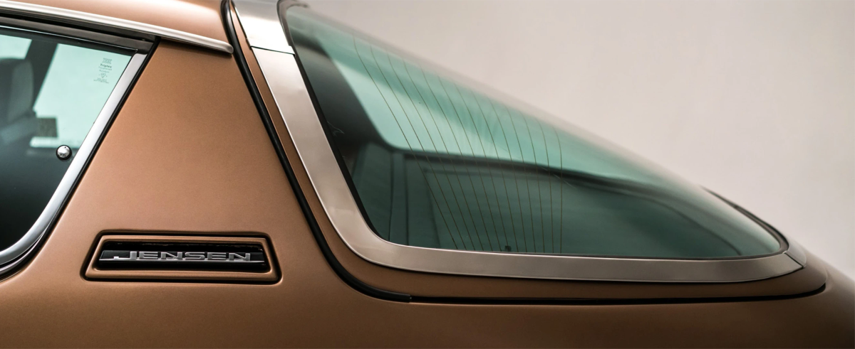 Close-up of the rear quarter window and 'Jensen' badge on a bronze car's bodywork