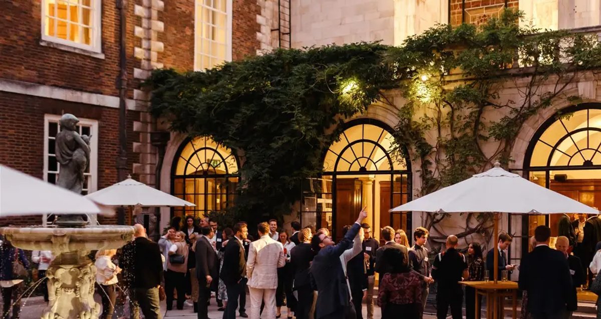 The Merchant Taylors event on a summer evening with several people dressed in suits standing outside.
