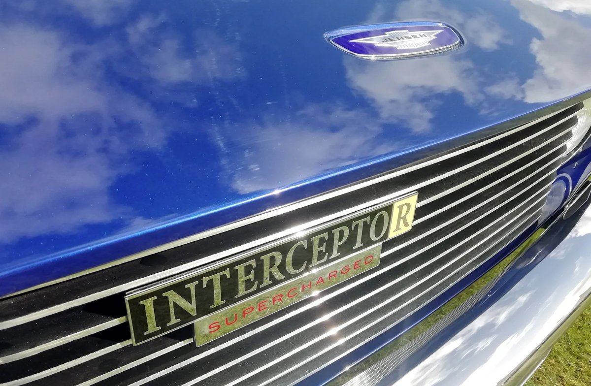 Close-up of the 'Interceptor R Supercharged' badge and Jensen winged emblem on a blue car's bonnet