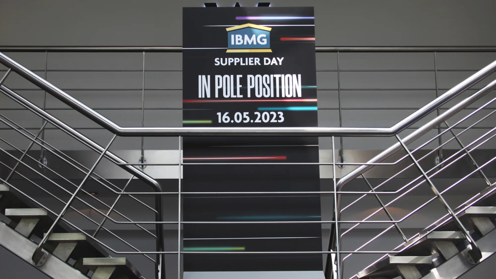 Tall banner above a staircase reading "IBMG Supplier Day, In Pole Position, 16.05.2023"