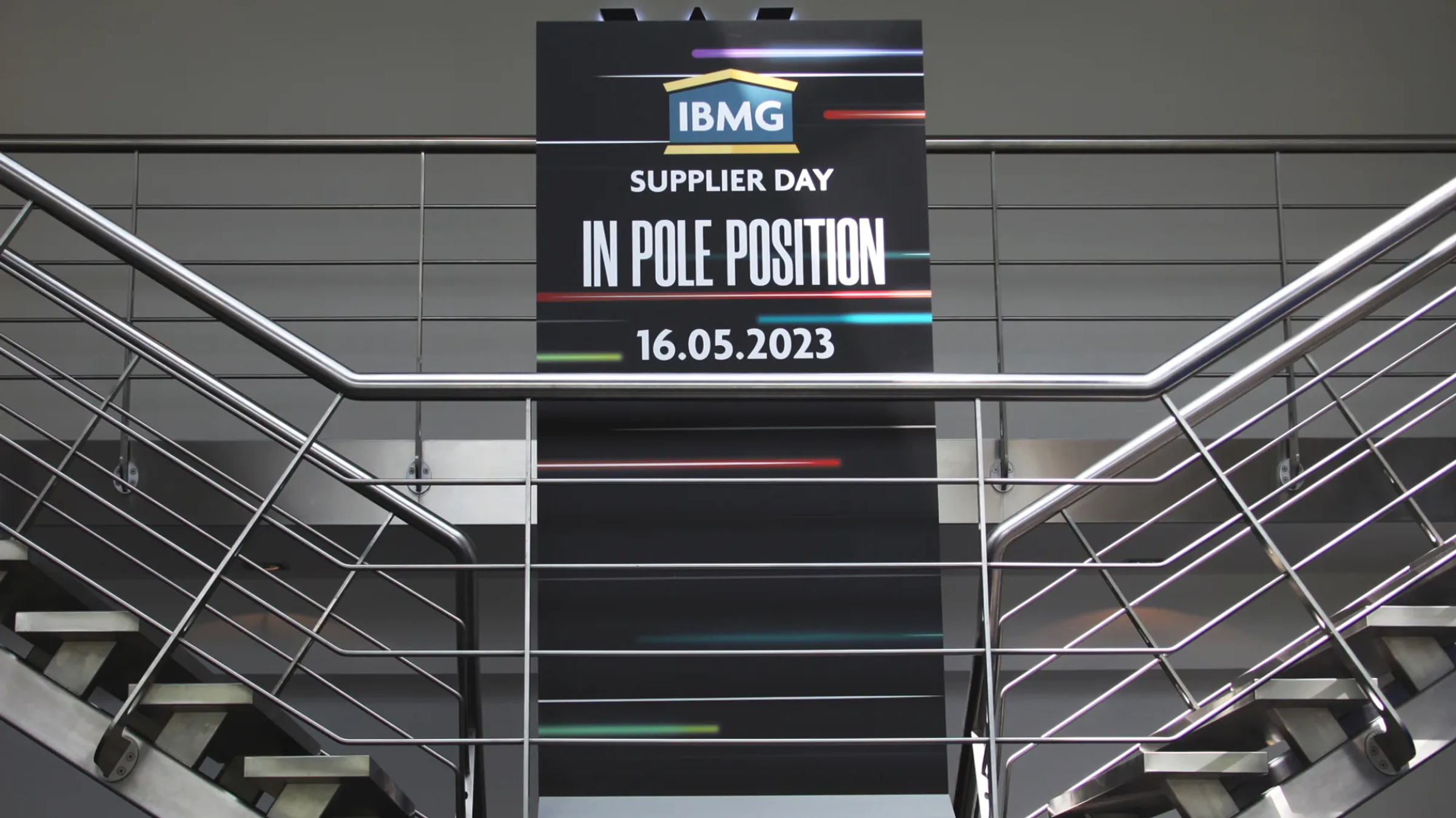 Tall banner above a staircase reading "IBMG Supplier Day, In Pole Position, 16.05.2023"