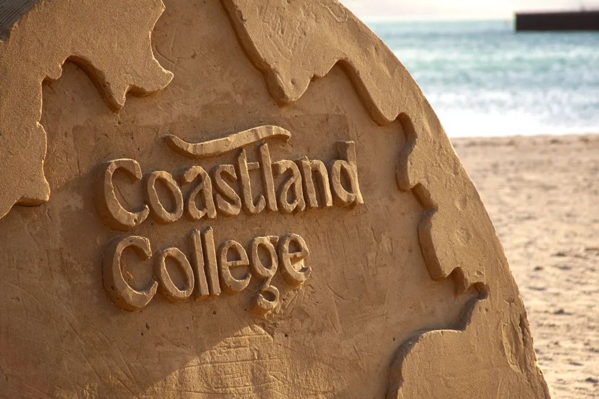 The Coastland College team on a beach with their branded Land Rover