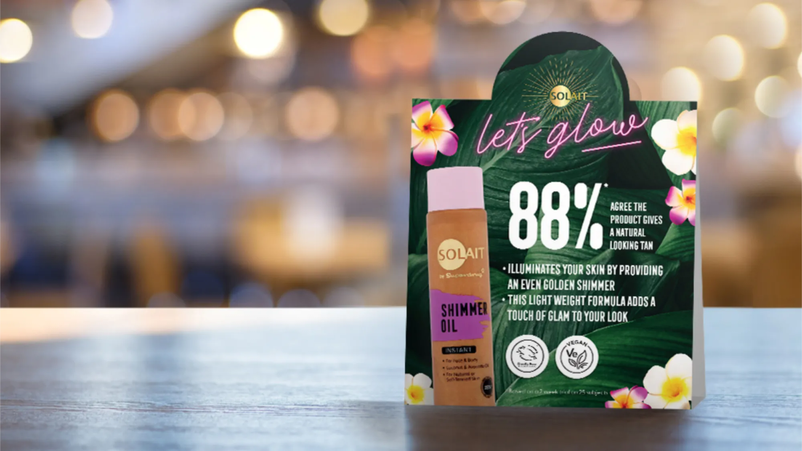 Solait tabletop advert with leafy backgrounds and 'neon' effect typography that is advertising a bronzing oil.