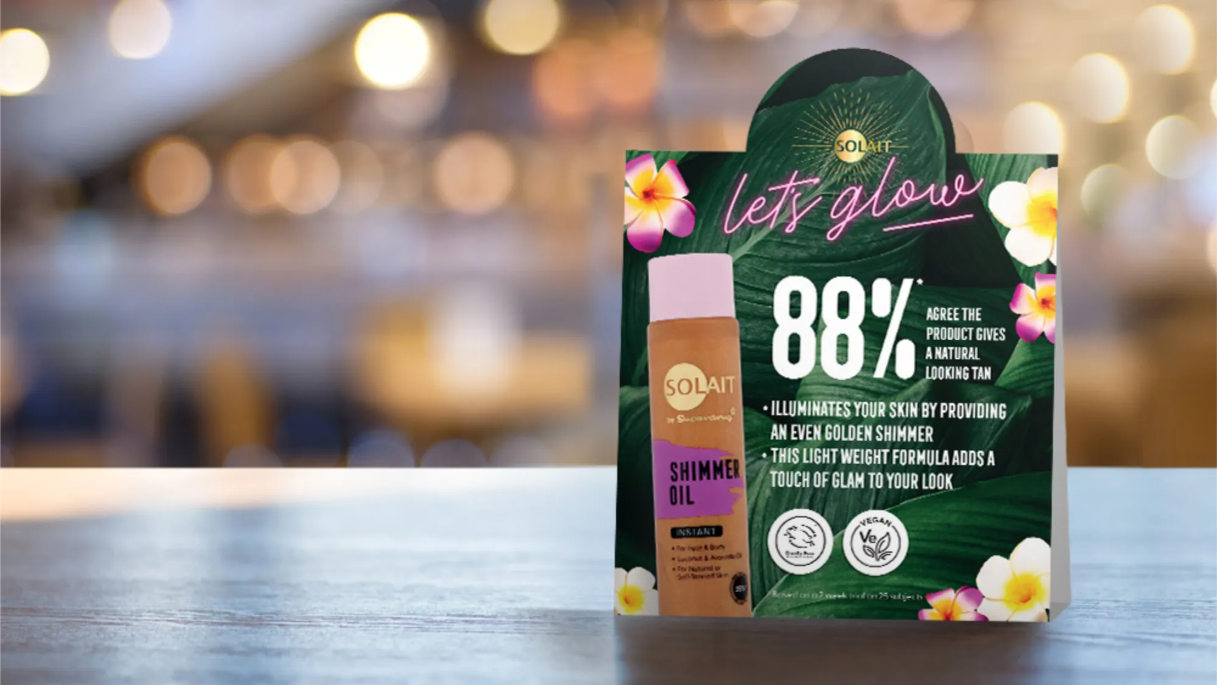 Solait tabletop advert with leafy backgrounds and 'neon' effect typography that is advertising a bronzing oil.