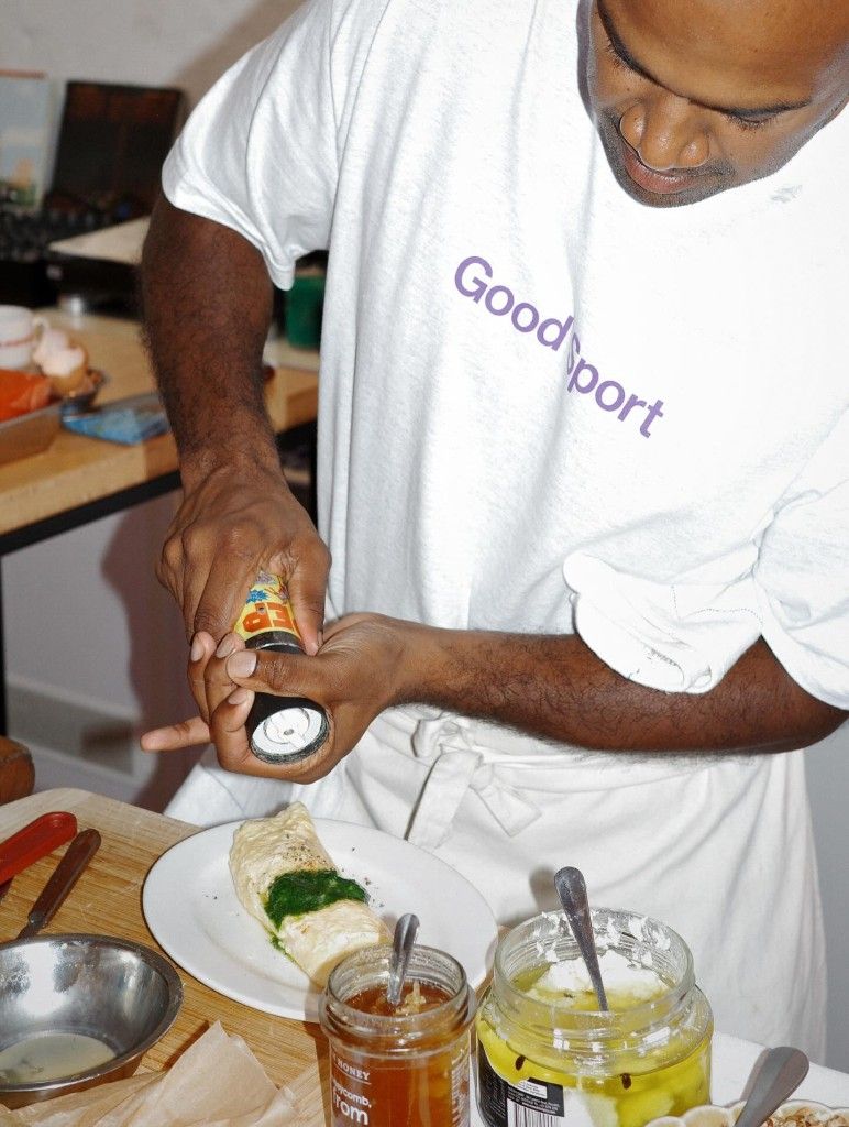Dishan finishing a plated dish, wearing a Goodsport t-shirt