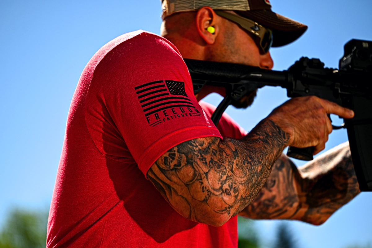Man holding a sighted rifle, wearing a Freedom Fatigues T-Shirt