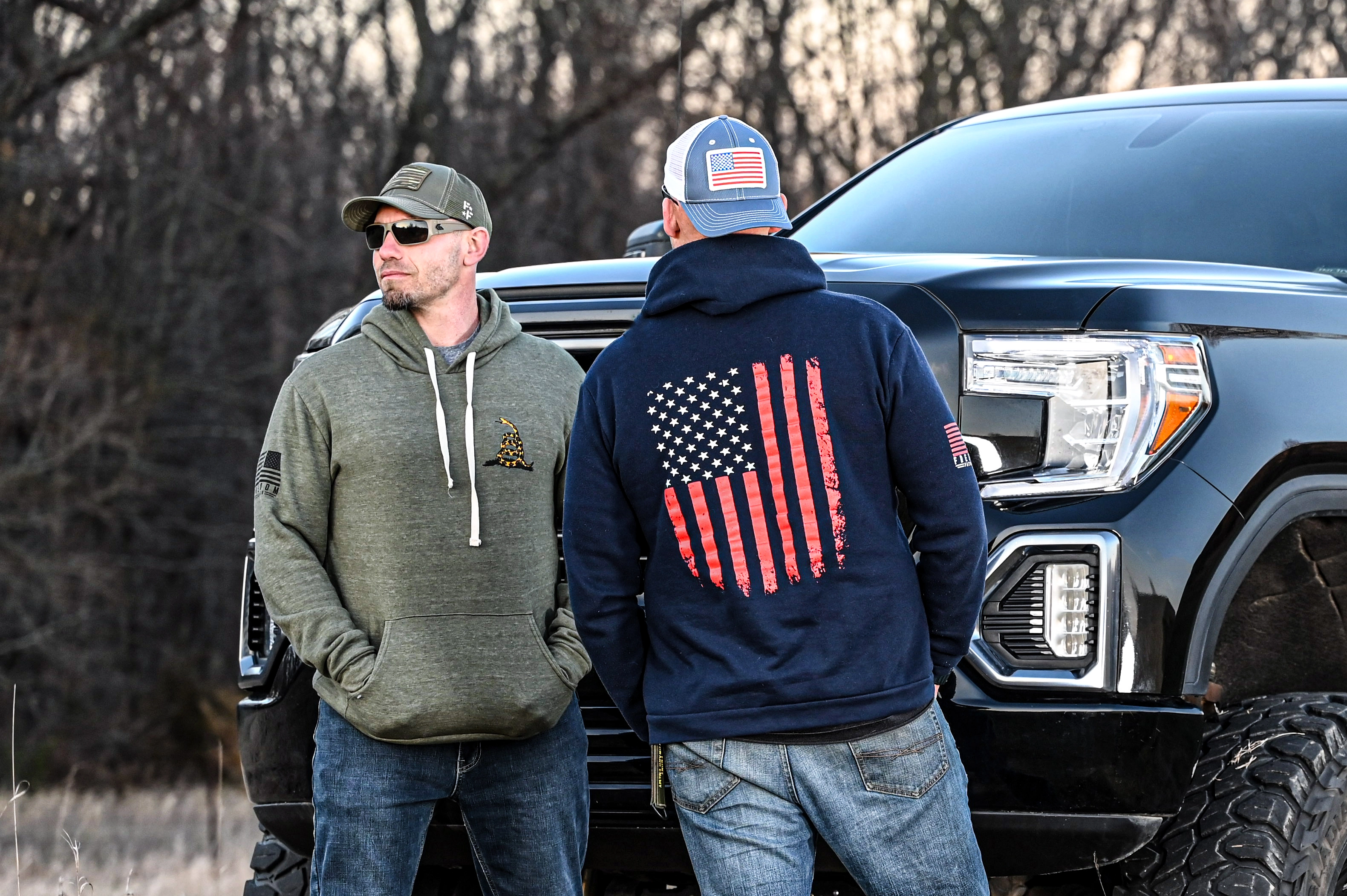2 Men Standing in front of a truck in patriotic hoodies and hats