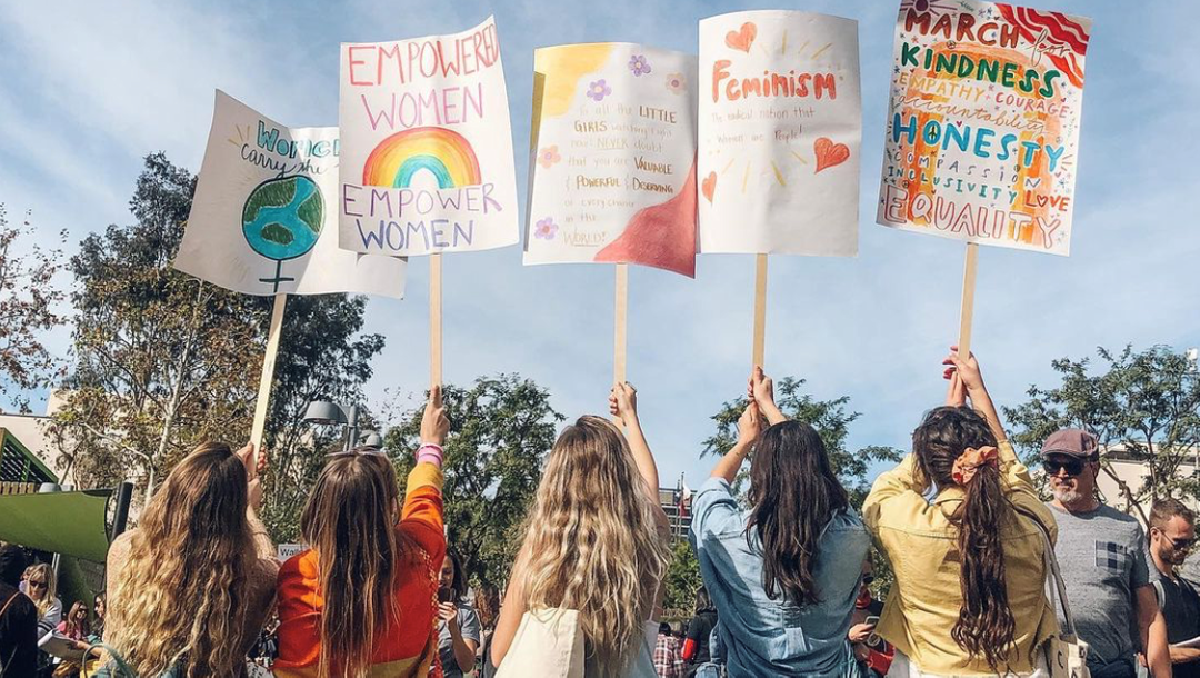 Women at women's march holding climate and feminism signs