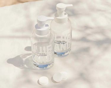 Hand Soap Duo: 2 refillable glass Forever Bottles on white blanket with shadow of tree