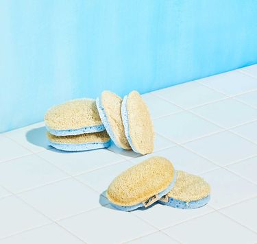 6 Scrub Sponges with yellow loofah side on blue sponge on white tile with blue background