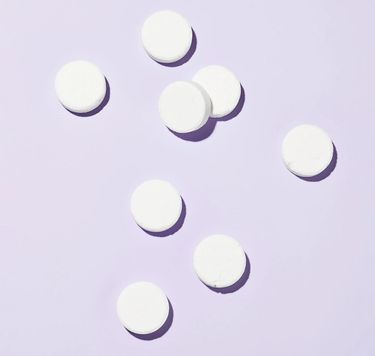 8 white plastic-free toilet bowl cleaner tablets against purple background