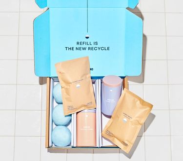 Laundry Essentials Kit in blue cardboard box: 2 refillable Forever tins, 2 compostable refill pouches, 3 wool dryer balls