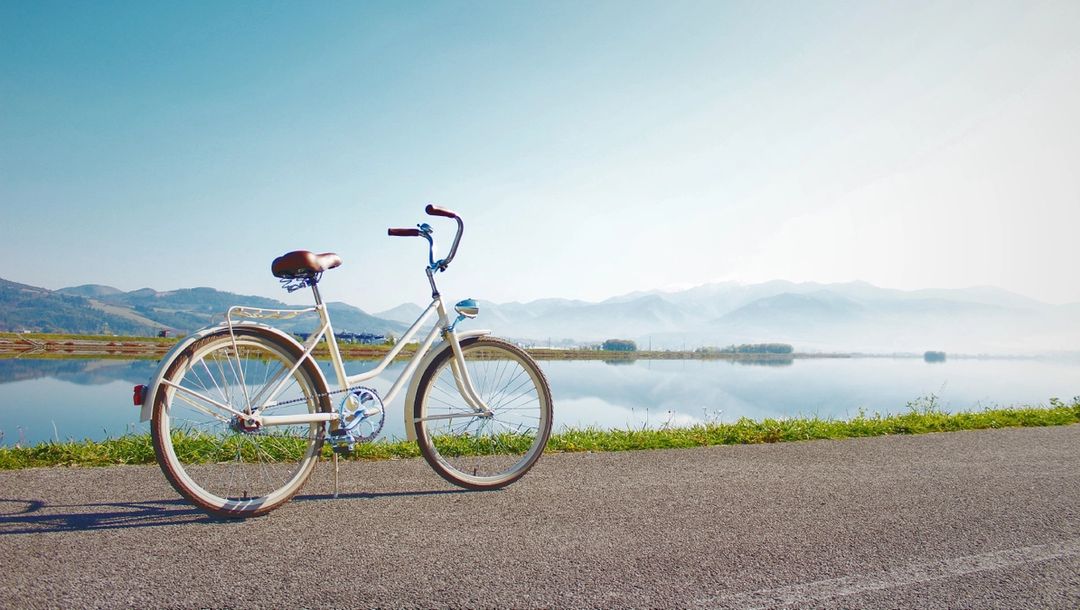 Bike on a road against a lake with mountains in the background