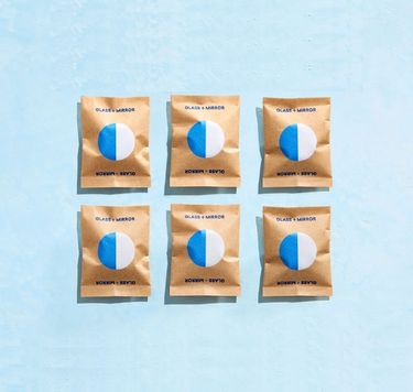 6 Blueland Glass + Mirror refill tablets in compostable wrappers against blue background