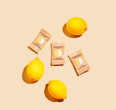 Multi-Surface Cleaning Spray: 3 wrapped tablets in compostable wrappers against yellow background with lemons surrounding