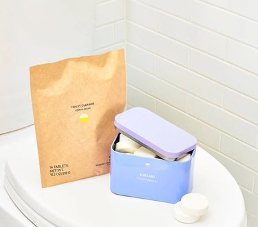 Toilet Bowl Cleaner Starter Set on toilet seat: 1 Forever Tin ajar with tablets inside next to compostable refill pouch