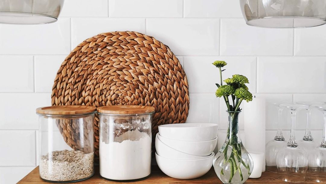 Kitchen pantry with glass jars holding grains and flour, bowls and a green flower vase