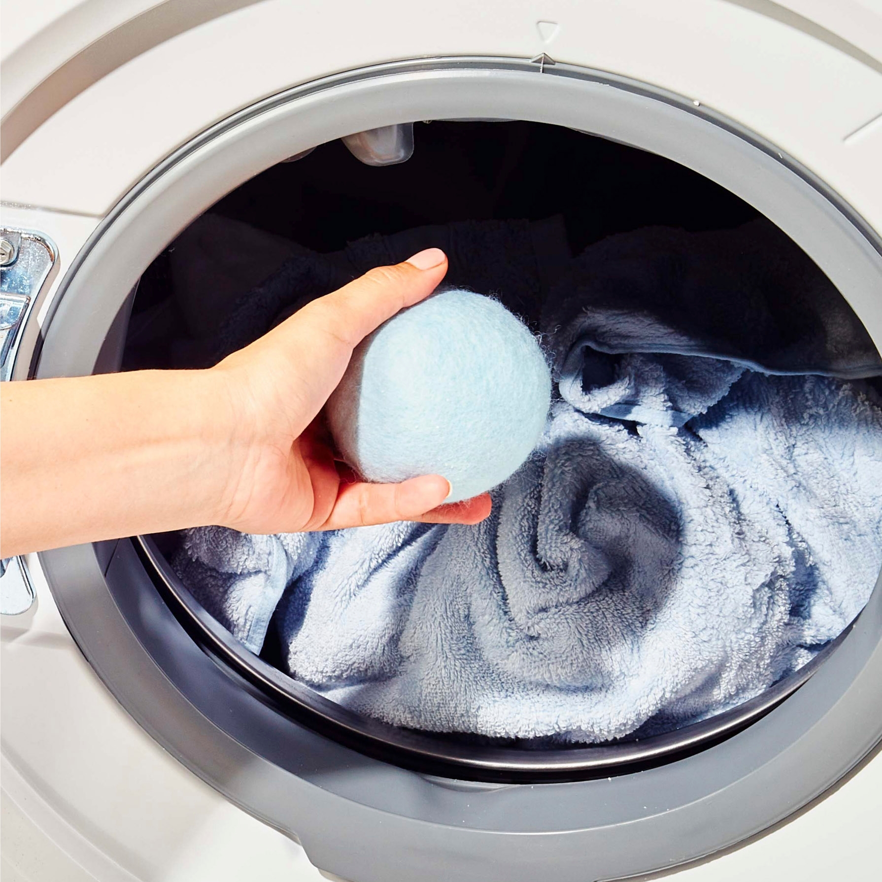 Blueland Wool Dryer Ball being placed inside dryer