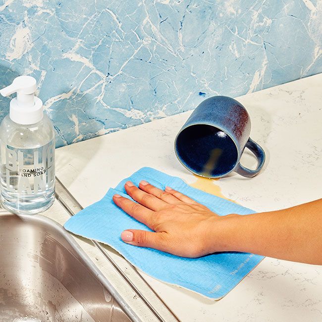 Light blue Cloud Cloth wipes spill from ceramic blue mug next to sink with adjacent Foaming Hand Soap bottle