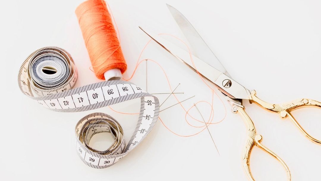 Scissors, measuring tape and orange thread