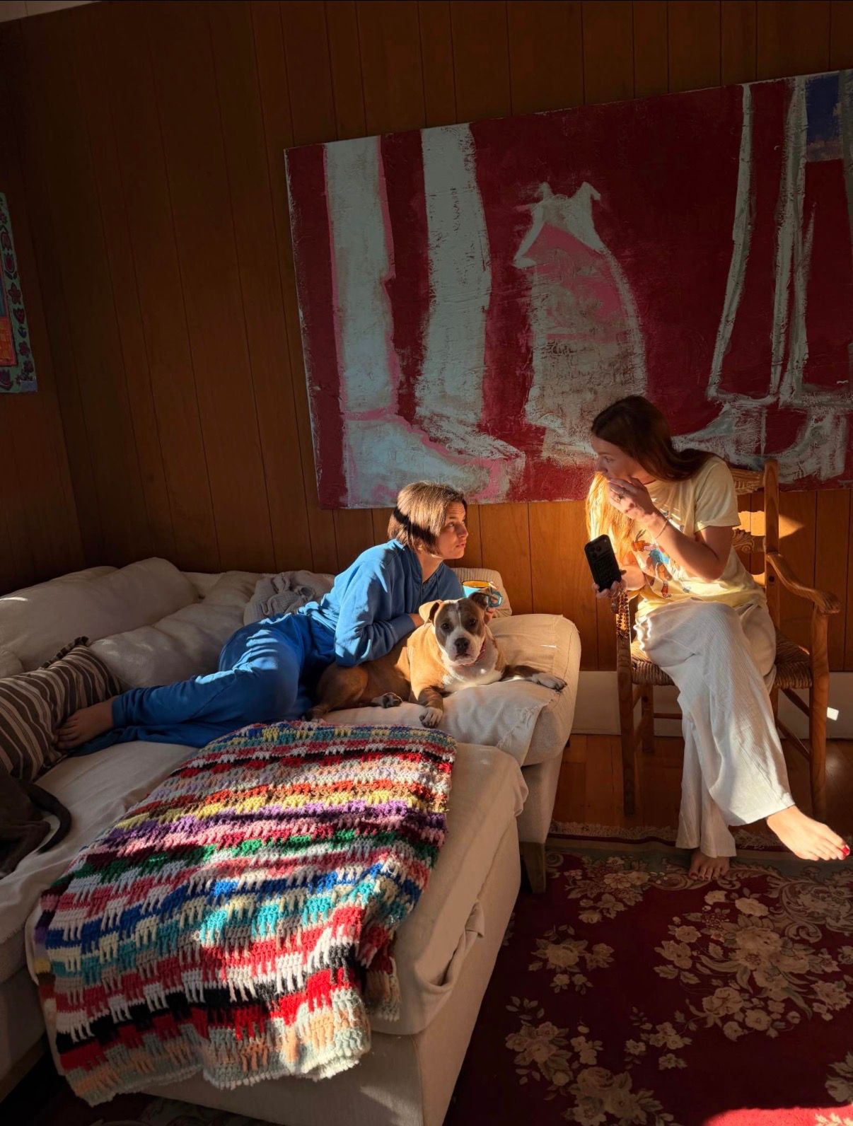 Huge abstract painting in reds and blues with two girls and a dog in front