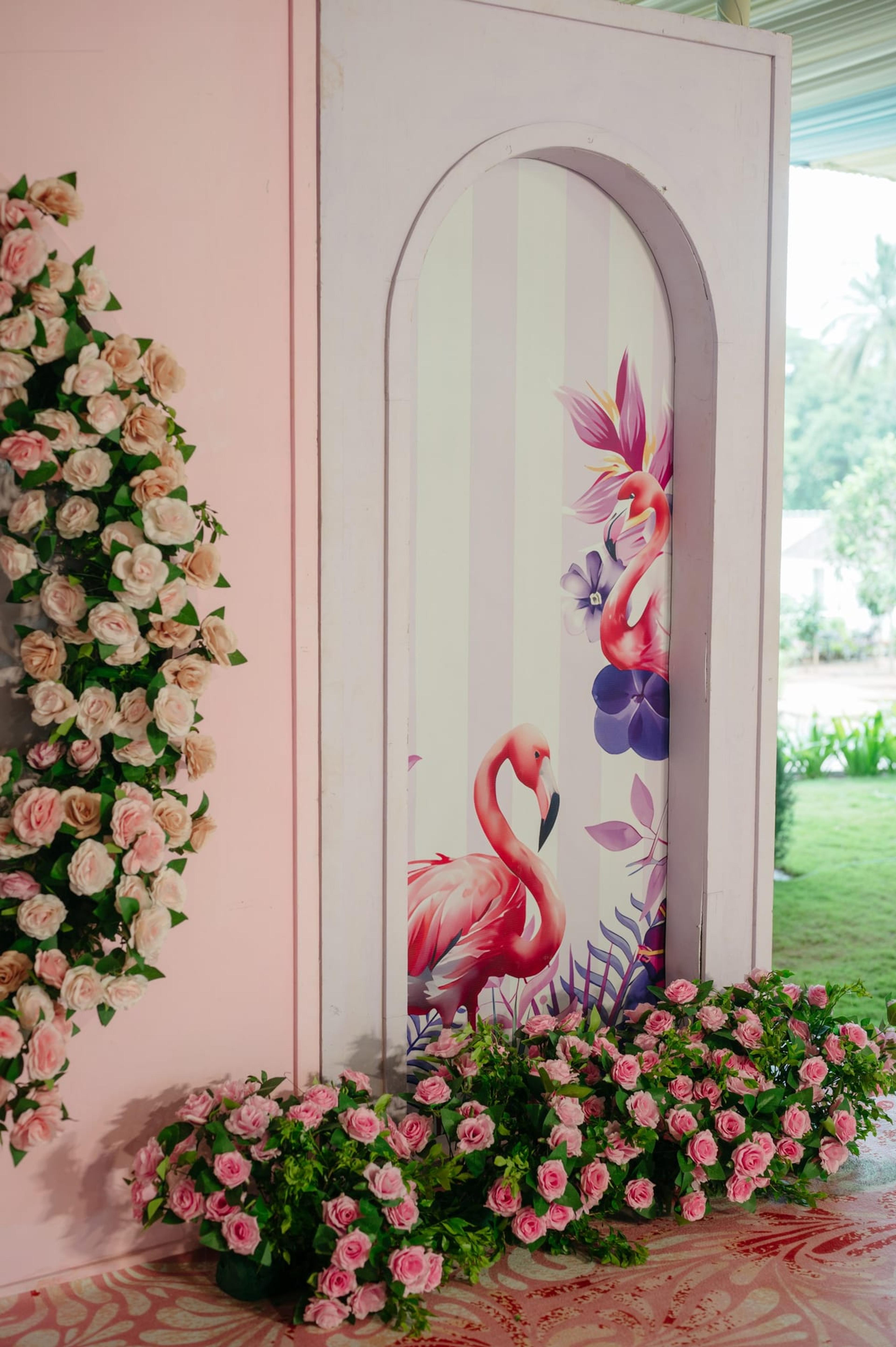 An opulent peacock-shaped floral stage backdrop in blush, pink and pastel blooms framing a decorated mandap