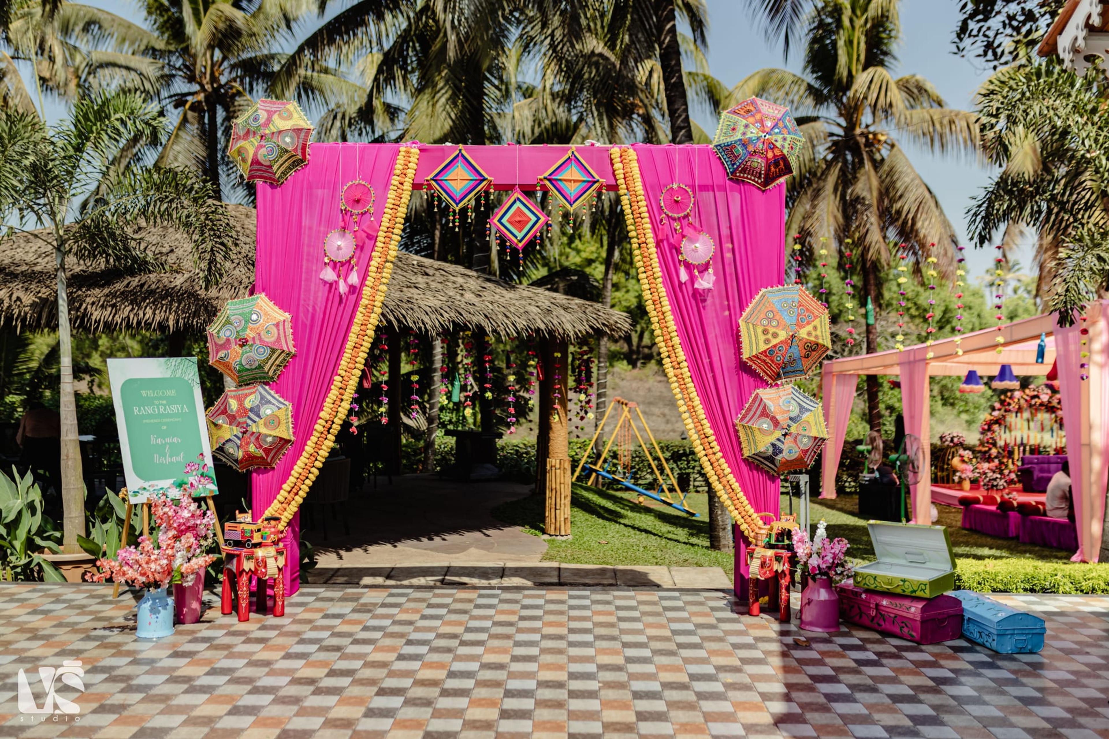 A towering coral and blush floral arch installation framed by palms at a tropical resort wedding