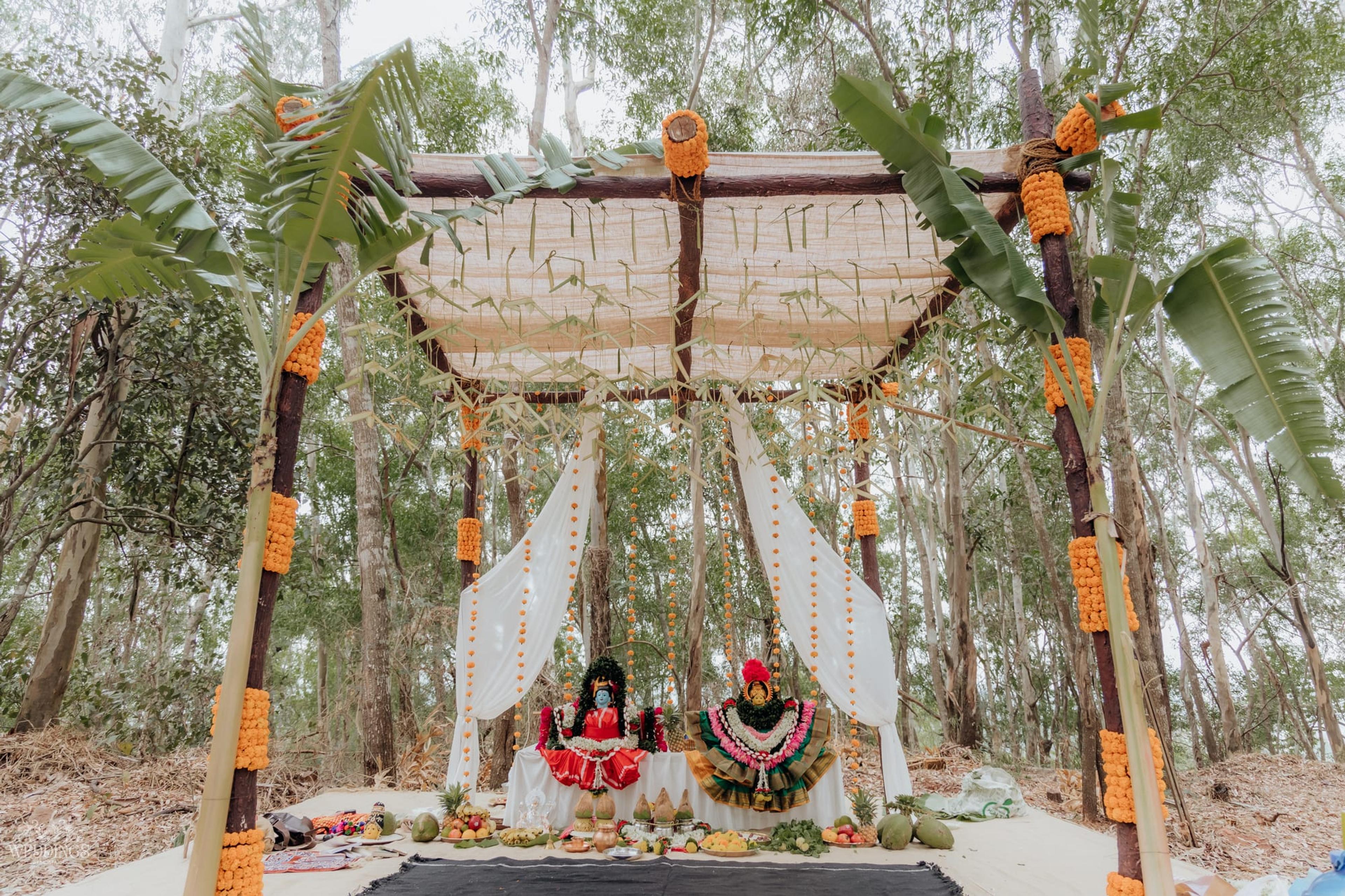 A lush hot-pink and blush floral installation suspended among woodland trees at a forest wedding