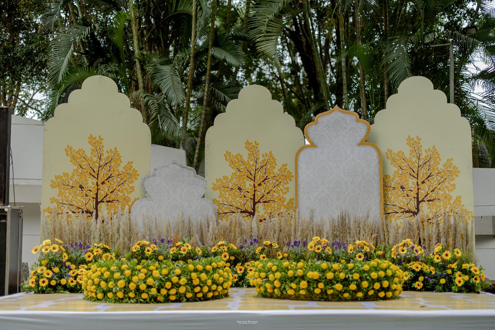 Cream arched panels with golden tree motifs above lush beds of marigold blooms