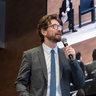 a man in a suit and tie is speaking into a microphone