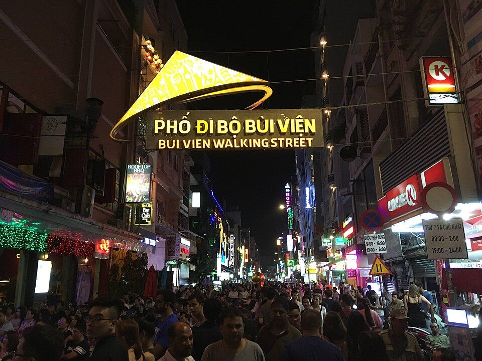 People exploring Bùi Viện Walking Street beneath illuminated signs at night
