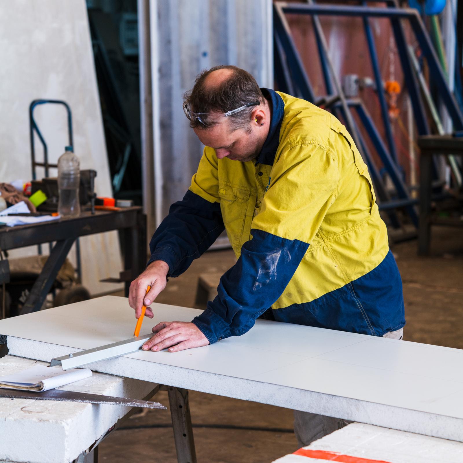 A maker at a workshop bench, head down over detailed work