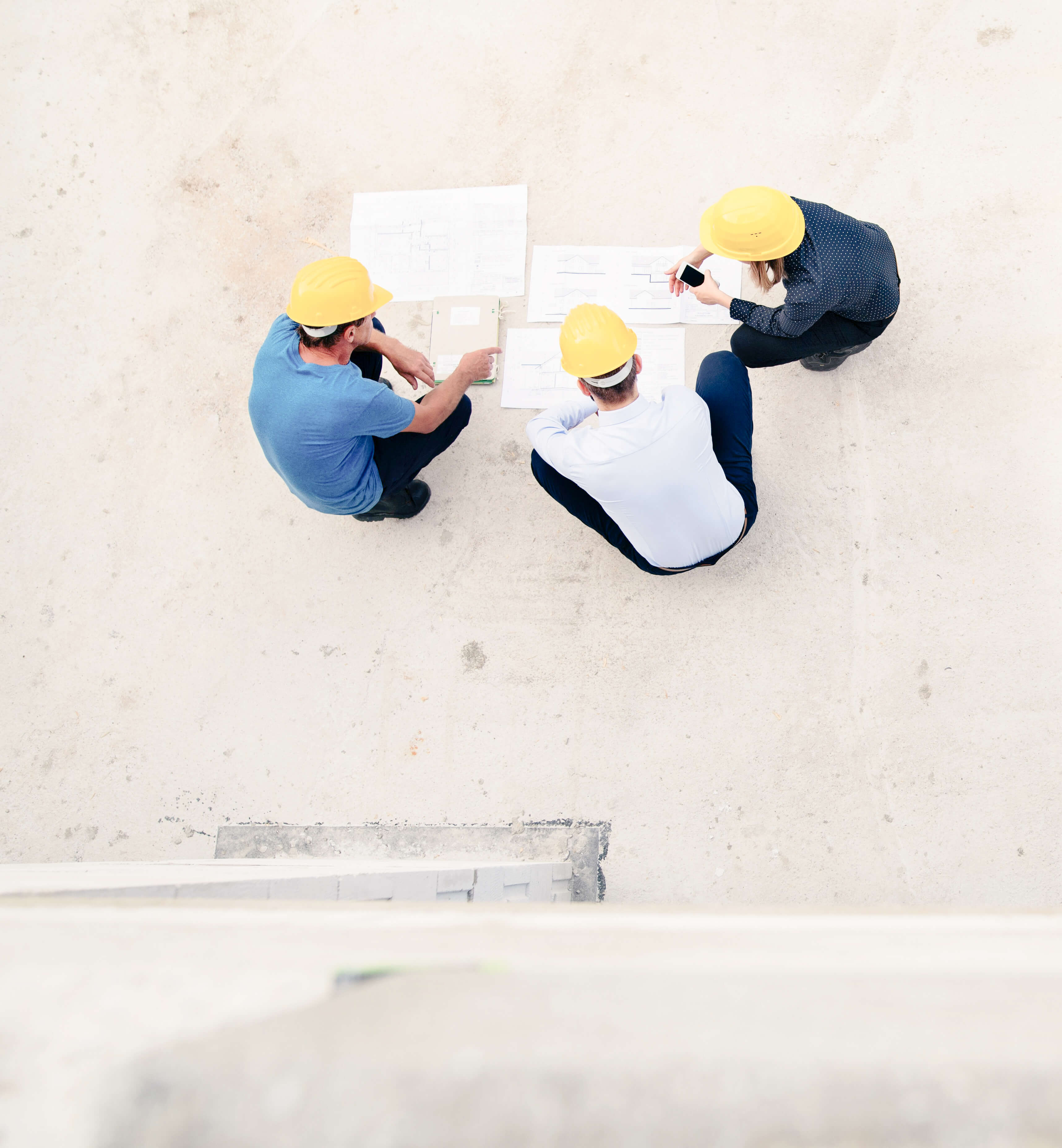 The site team gathered over drawings, seen from above