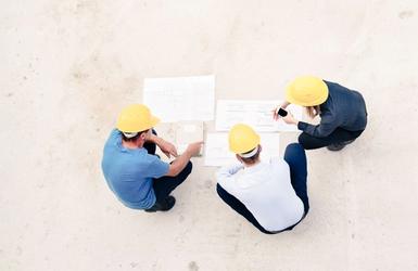 The site team gathered over drawings, seen from above