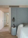 The master bedroom in woven grey panelling, corridor beyond